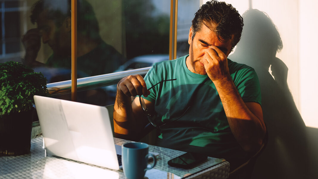 Stressed out mature man working from home sitting on the balcony