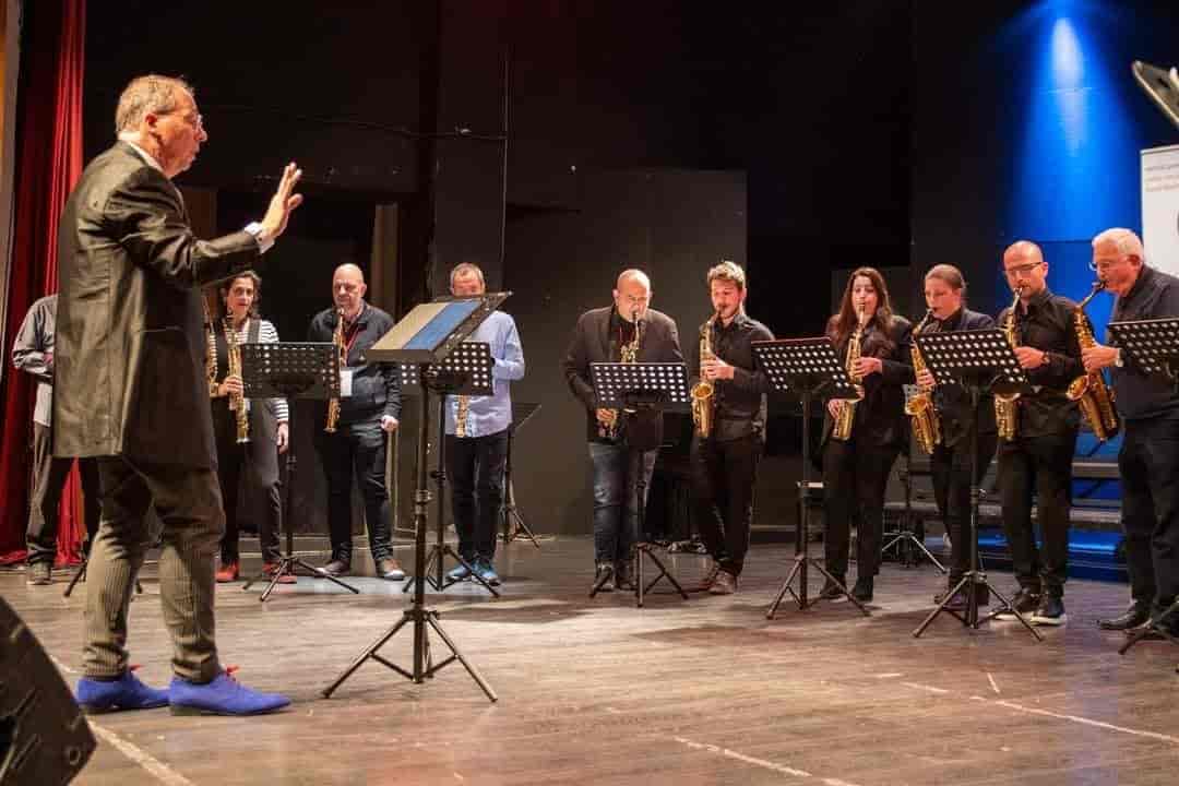 Το Σαξόφωνο στο Δημοτικό Ωδείο Λάρισας: Ένας Κόσμος Δημιουργίας και Καινοτομίας
Το σαξόφωνο, ένα από τα πιο αγαπητά και ευέλικτα μουσικά όργανα, συνδυάζει τον μοντέρνο ήχο με την κλασική γοητεία. Η ζεστή, δυναμική του χροιά το καθιστά ιδιαίτερα προσιτό και ελκυστικό στους νέους, ενώ η δυνατότητά του να προσαρμόζεται σε διαφορετικά μουσικά είδη, από τη τζαζ μέχρι την κλασική μουσική, το καθιστά μοναδικό.
Το Δημοτικό Ωδείο Λάρισας έχει αγκαλιάσει τη μαγεία του σαξοφώνου, αναγνωρίζοντας τη δυναμική του να προσελκύει και να εμπνέει νέες γενιές μουσικών. Η τάξη σαξοφώνου, υπό την καθοδήγηση του καταξιωμένου καθηγητή Αθανάσιου Φυσέκη, λειτουργεί εδώ και 11 χρόνια, δημιουργώντας ένα κέντρο μουσικής αριστείας. Κατά τη διάρκεια αυτής της περιόδου, οι μαθητές της τάξης έχουν επιτύχει σημαντικές διακρίσεις, όπως πτυχία, διπλώματα, και εντυπωσιακές συναυλίες που αναδεικνύουν το ταλέντο και την αφοσίωσή τους.
Η Υποστήριξη του Ωδείου
Το Δημοτικό Ωδείο Λάρισας αποτελεί πυλώνα μουσικής εκπαίδευσης, καλλιεργώντας το ταλέντο με σύγχρονες προσεγγίσεις και υψηλή ποιότητα διδασκαλίας. Η διοίκησή του επενδύει σταθερά σε εξοπλισμό, συνεργασίες με διεθνείς φορείς και καινοτόμα προγράμματα. Μέσα από αυτές τις πρωτοβουλίες, η τάξη σαξοφώνου έχει καθιερωθεί ως πρότυπο μουσικής εκπαίδευσης, παρέχοντας στους σπουδαστές της ένα περιβάλλον δημιουργικής εξέλιξης και ακαδημαϊκής προοπτικής.
Το Διεθνές Φεστιβάλ Σαξοφώνου
Ένα από τα μεγαλύτερα επιτεύγματα της σχολής σαξοφώνου είναι το Διεθνές Φεστιβάλ Σαξοφώνου, που ξεκίνησε από τη δεύτερη κιόλας χρονιά της λειτουργίας της. Το φεστιβάλ αυτό έχει μετατραπεί σε έναν θεσμό, προσκαλώντας μουσικούς από όλο τον κόσμο, προσελκύοντας ταυτόχρονα το ενδιαφέρον των νέων όλης της χώρας μας, μιας και είναι το μοναδικό φεστιβάλ σαξοφώνου που διοργανώνεται στην Ελλάδα. Περιλαμβάνει διεθνείς διαγωνισμούς, σεμινάρια, διαλέξεις και συναυλίες που εμπλουτίζουν τη μουσική κουλτούρα της Λάρισας.
Μερικές από τις μεγαλύτερες προσωπικότητες του σαξοφώνου έχουν τιμήσει με την παρουσία τους το φεστιβάλ, όπως ο θρύλος Jean-Marie Londeix, ο κορυφαίος σολίστ Nikita Zimin, ο Γιώργος Κατσαρός και πολλοί άλλοι. Οι συμμετέχοντες έχουν την ευκαιρία να διδαχθούν από καταξιωμένους καθηγητές και να εμπνευστούν από τις εμπειρίες τους, δημιουργώντας ένα μοναδικό περιβάλλον ανταλλαγής γνώσεων και ιδεών.
Ένα φεστιβάλ με προοπτικές
Το Διεθνές Φεστιβάλ Σαξοφώνου του Δημοτικού Ωδείου Λάρισας αποτελεί πυρήνα πολιτιστικής άνθησης, ενώνοντας νέους ανθρώπους με καταξιωμένους καλλιτέχνες σε ένα γόνιμο περιβάλλον έμπνευσης και δημιουργίας. Αναδεικνύοντας την αξία του σαξοφώνου, το φεστιβάλ προσφέρει στους συμμετέχοντες μοναδικές ευκαιρίες να χτίσουν σχέσεις, να ανταλλάξουν ιδέες και να διαμορφώσουν το καλλιτεχνικό τους μέλλον, εδραιώνοντας τη Λάρισα ως σημείο αναφοράς στον διεθνή πολιτιστικό χάρτη.
